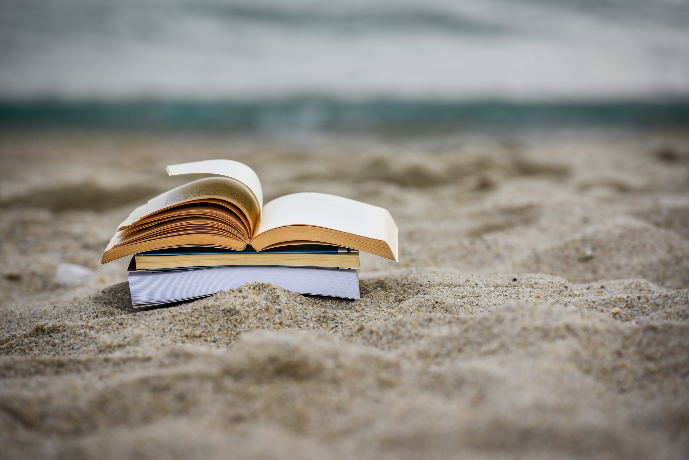 Open book at beach during summer by the sea. Reading summer book